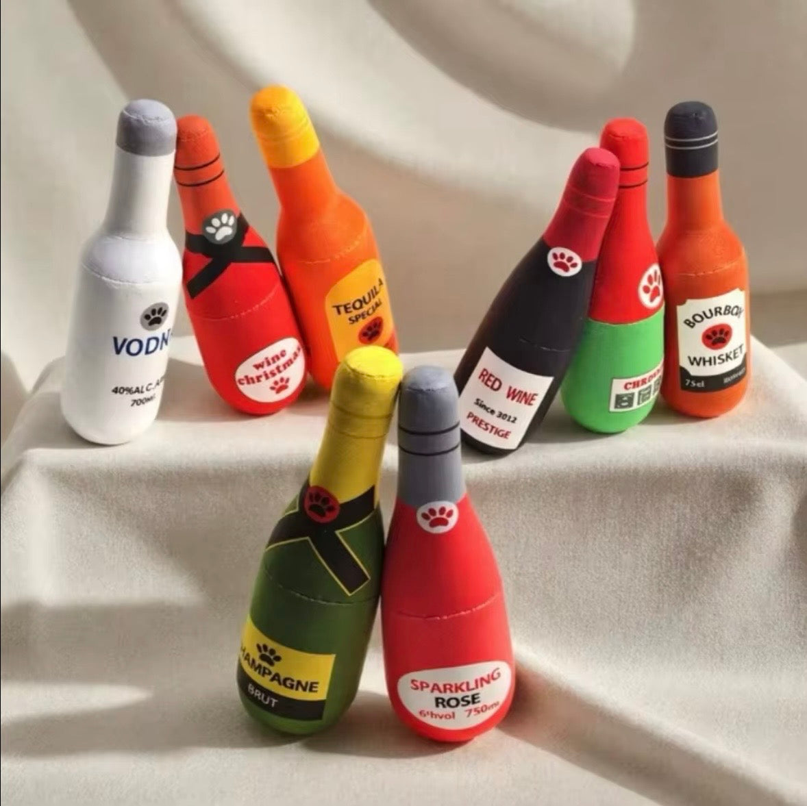 plush, squeaky bottle-shaped toys designed for dogs and cats, featuring various liquor and wine brand parodies.