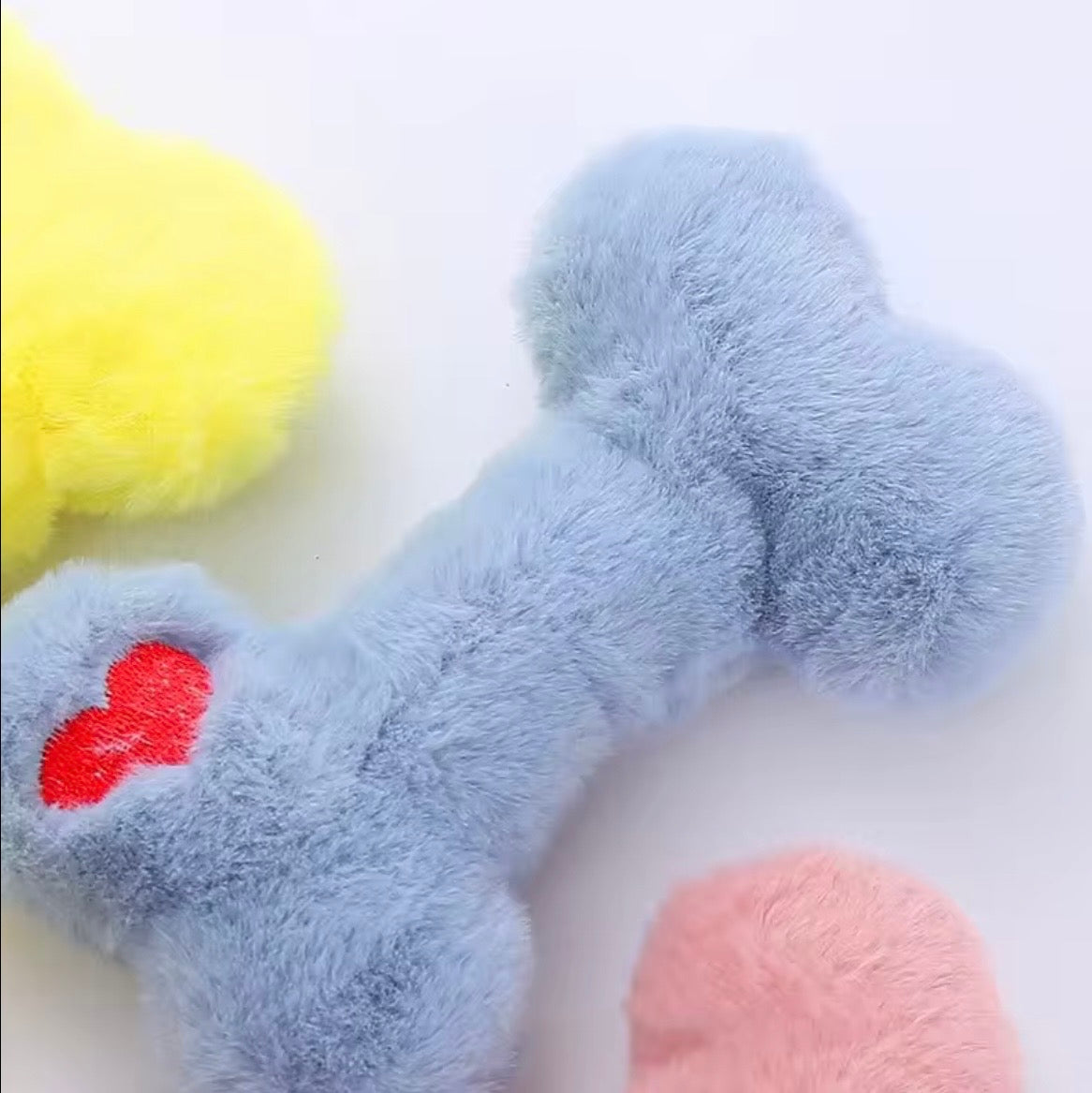 Funny Bone Squeaky Plush Dog Toys available in yellow, blue, and pink