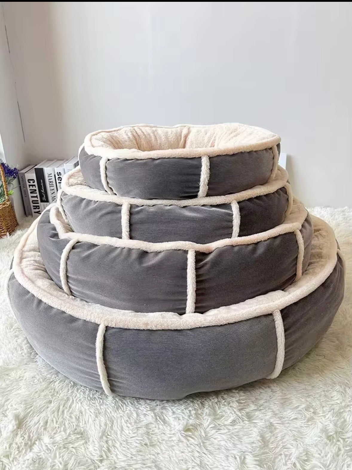 round, bolstered pet bed featuring a dark grey corduroy exterior and a soft, cream-colored plush interior.